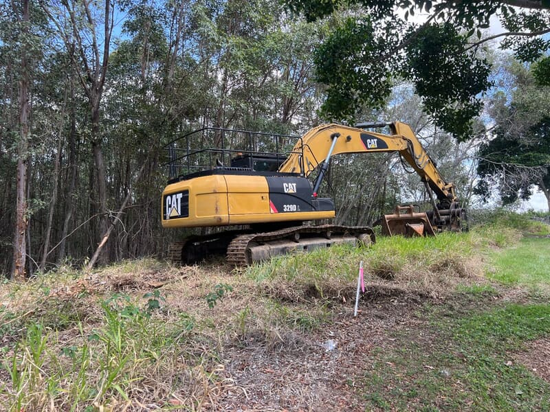CAT 329D excavator staged at the edge of the treed Browns Plains block