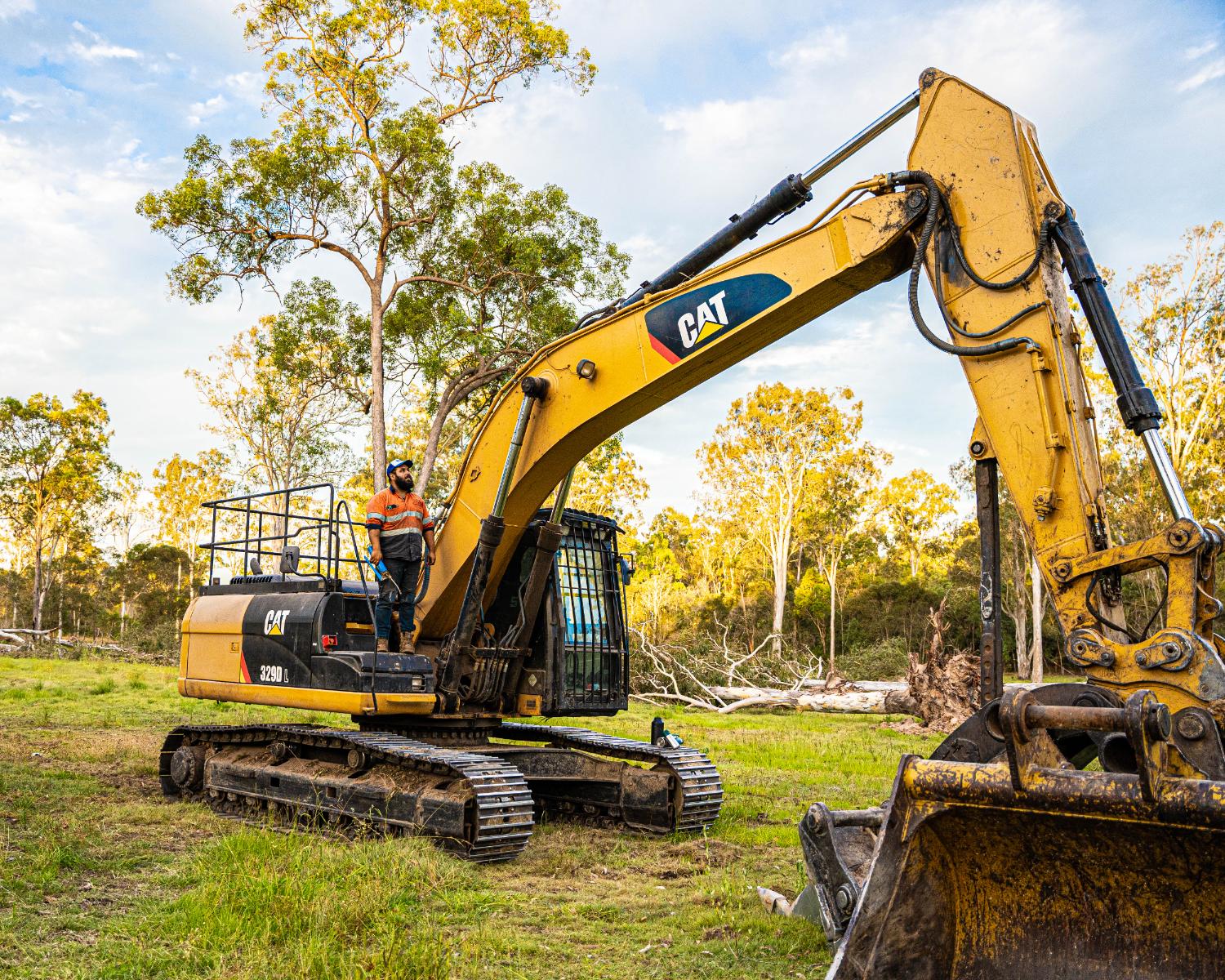 Operator standing on a CAT 329D excavator on a bush block