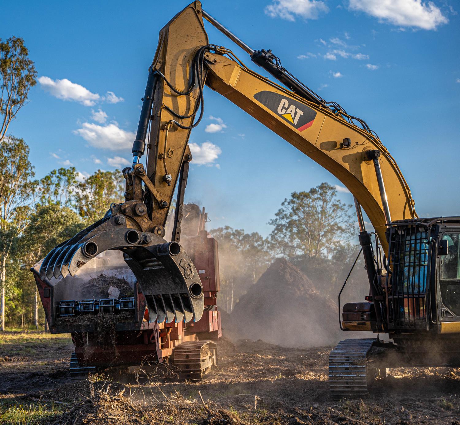 Grinder discharging mulch under a blue sky