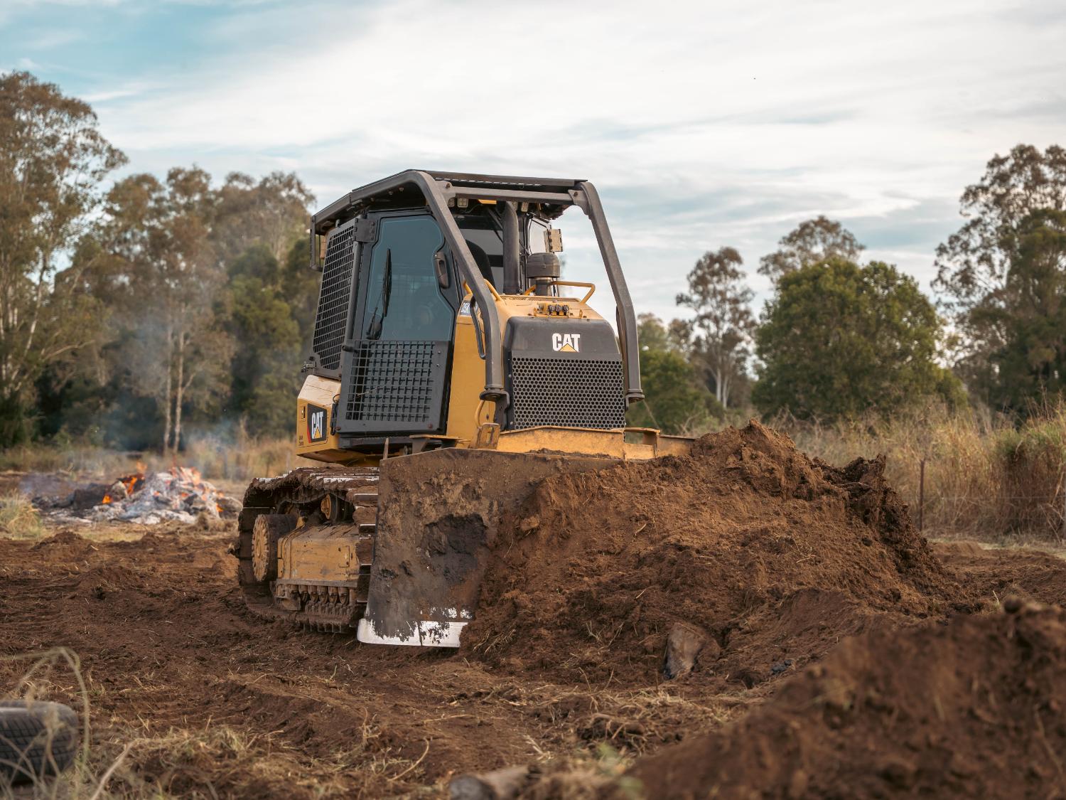 Excavator carrying a large log across a cleared block