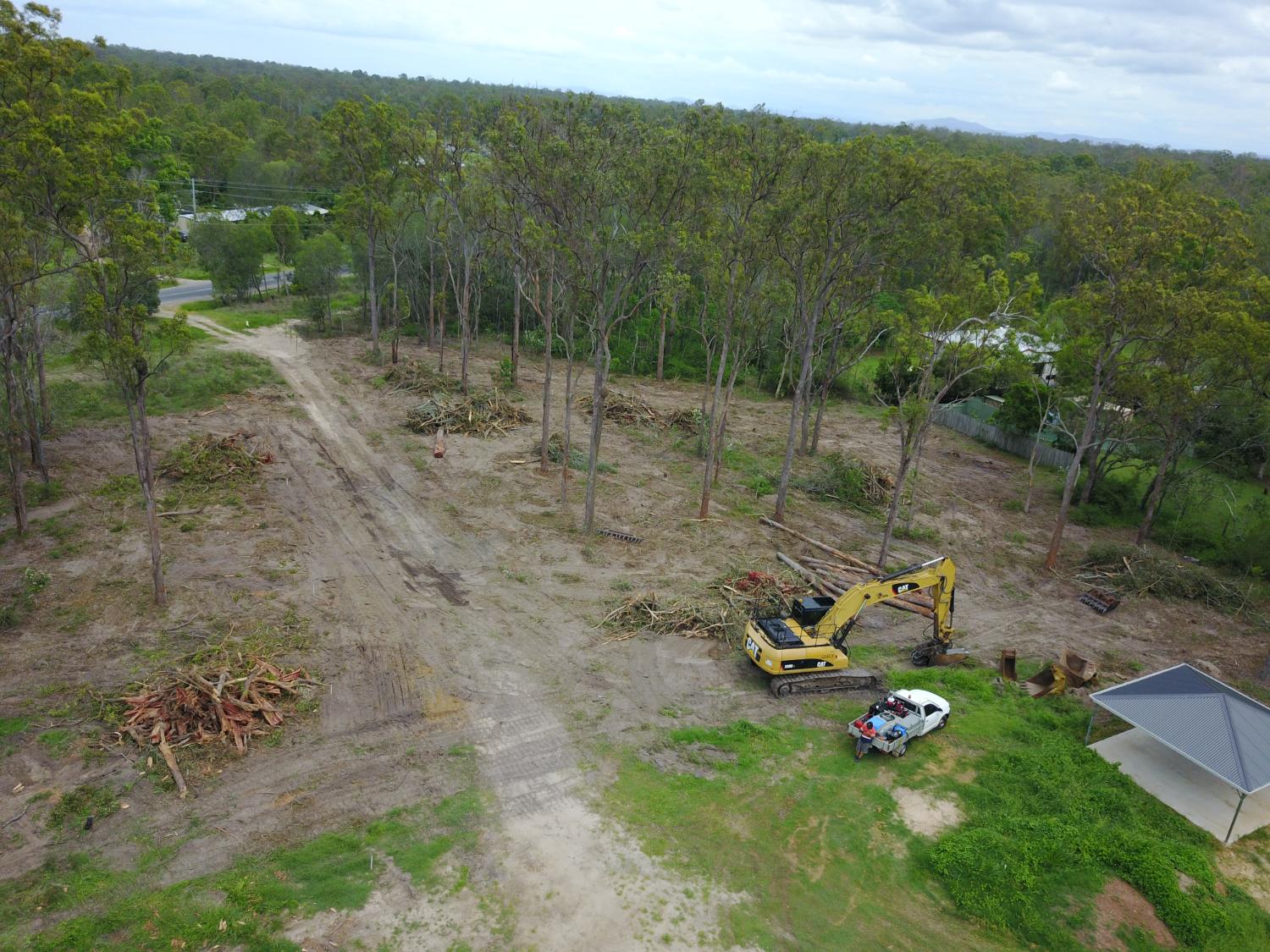 Wide aerial of a partly cleared property with mulch piles