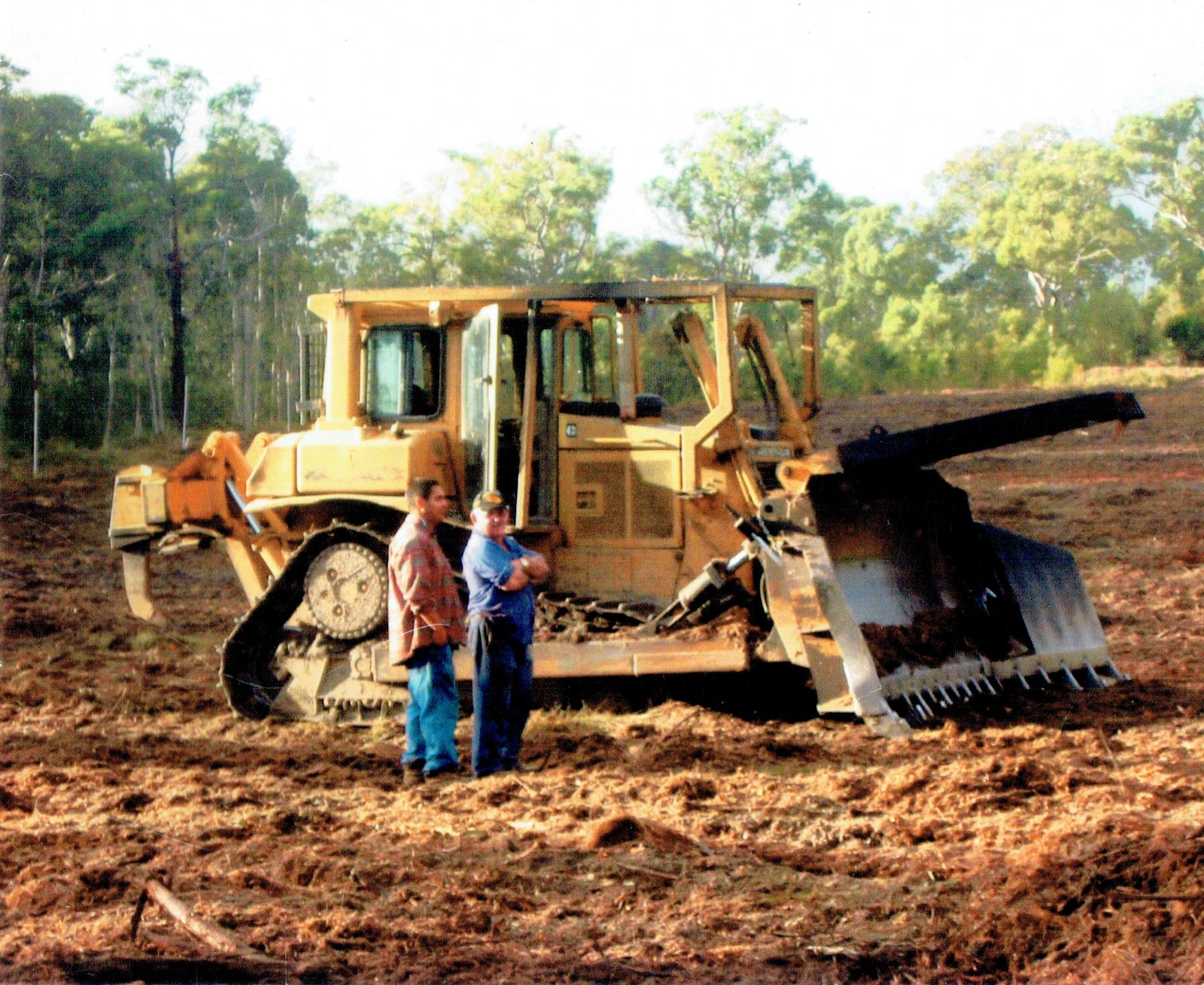 Two generations of the Tree Eaters family beside a CAT D6H Series II dozer with stick rake