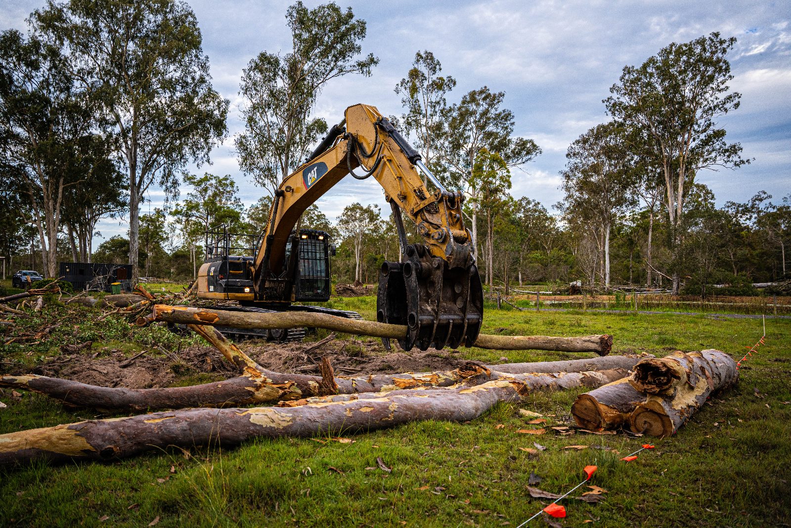 Tree Eaters excavator grapple lifting a salvaged log on a residential block