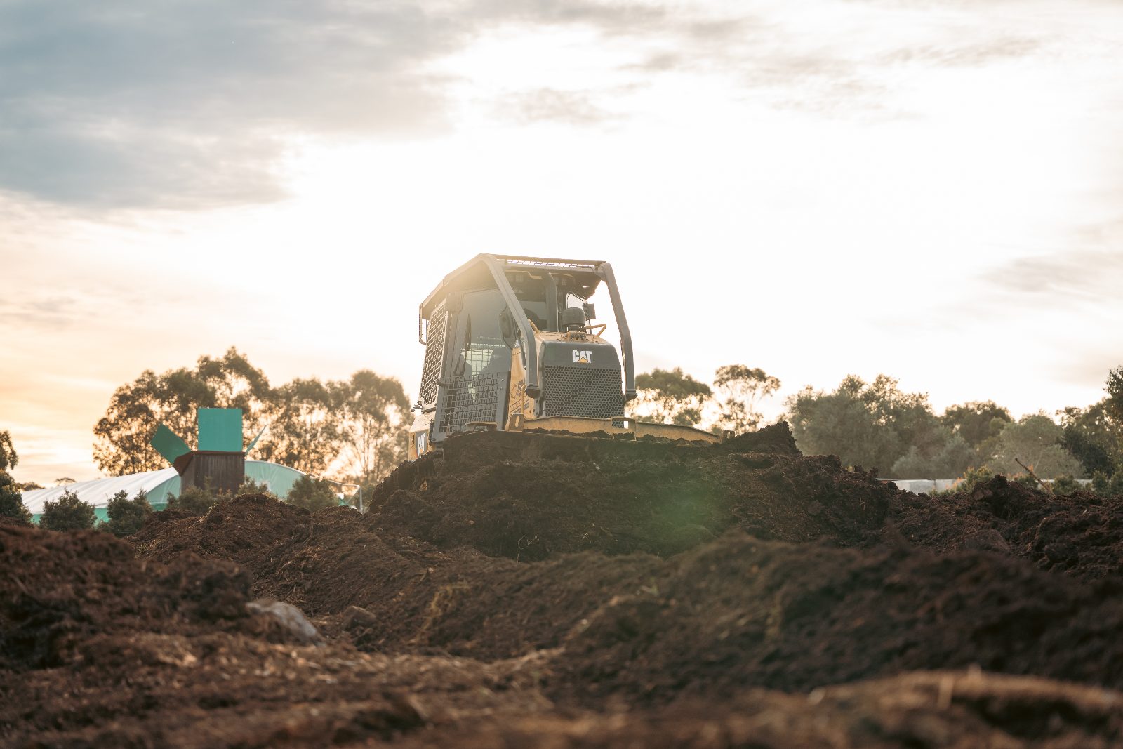 Dozer spreading mulch at sunset