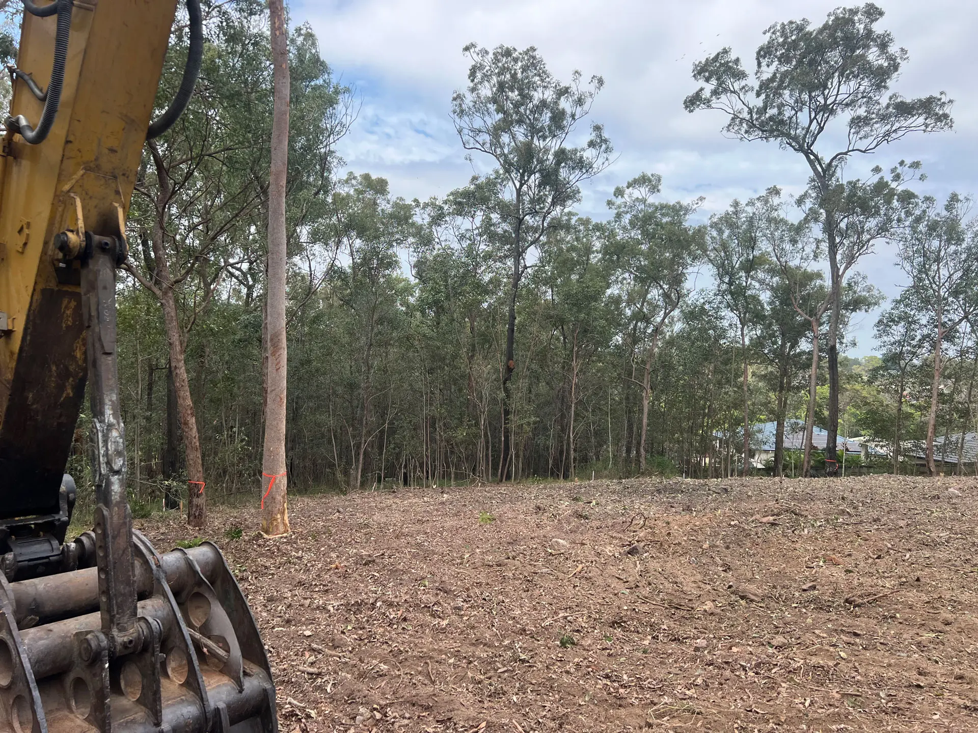 Tree Eaters excavator grapple lifting a salvaged log on a residential block