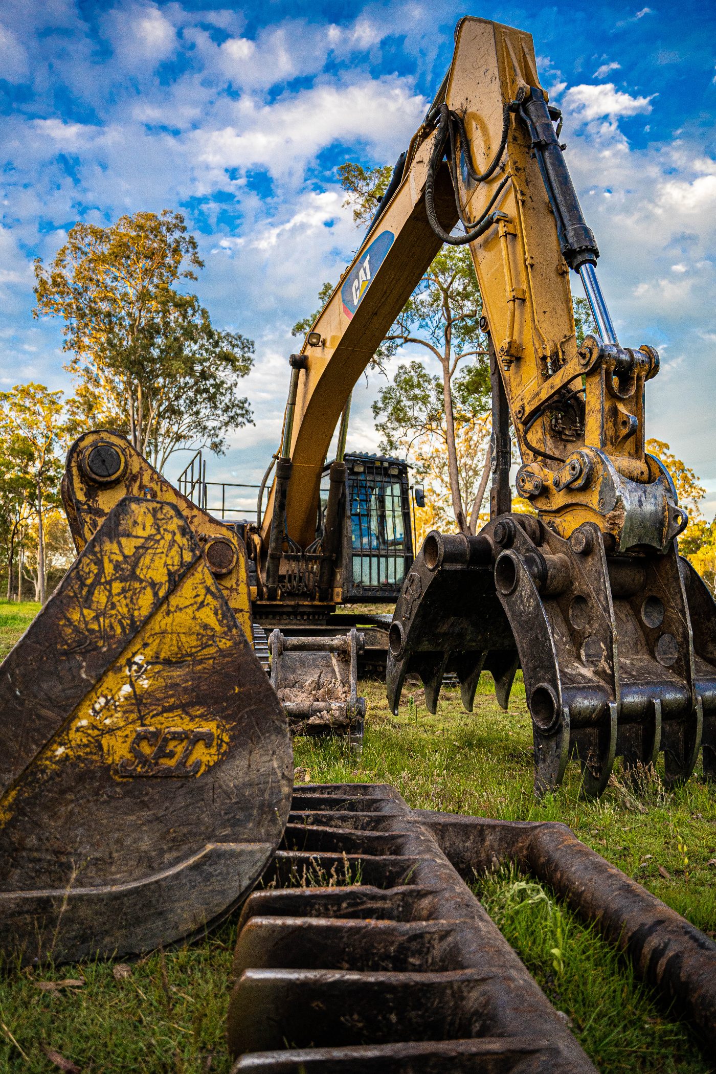 Tree Eaters excavator with bucket, grapple and stick rake attachments lined up on site