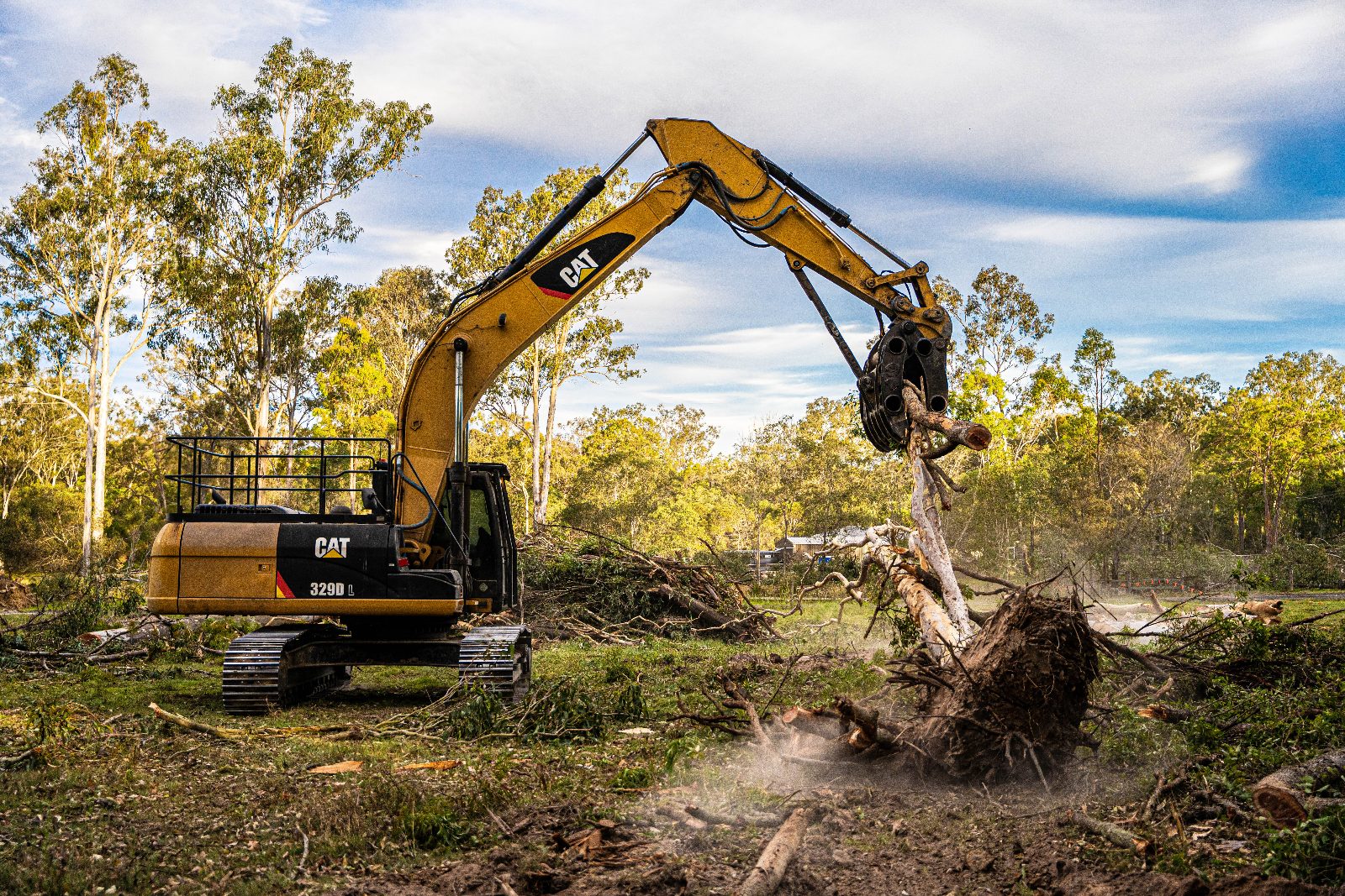 Tree Eaters excavator pulling a tree and root ball along a boundary line